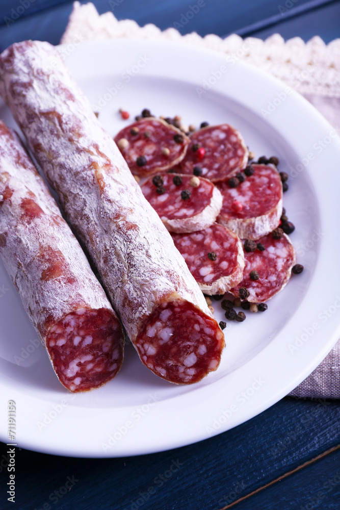 French salami on plate on napkin on dark blue wooden background French salami on plate on napkin on dark blue wooden background