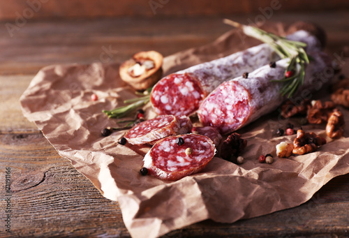 French salami and walnuts on craft paper on wooden background
