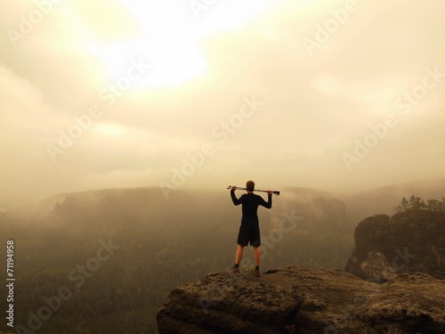 Tourist with pole standing on rocky view point above misty gulch © rdonar