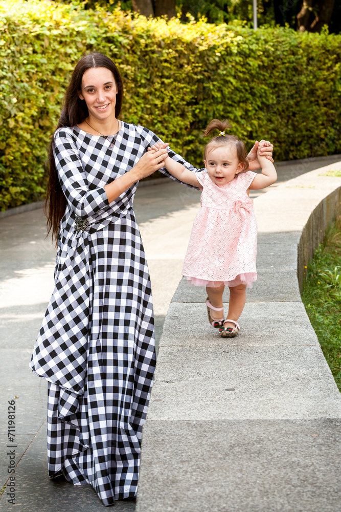 baby girl making first steps at park with mother baby girl making first steps at park with mother