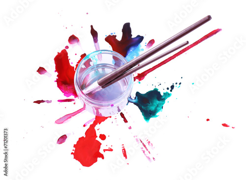 Brushes in glass jar with water and spilled paints isolated