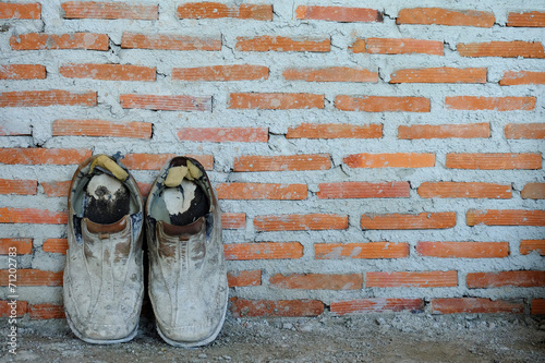 A pair of old shoes on brick wall background, old background