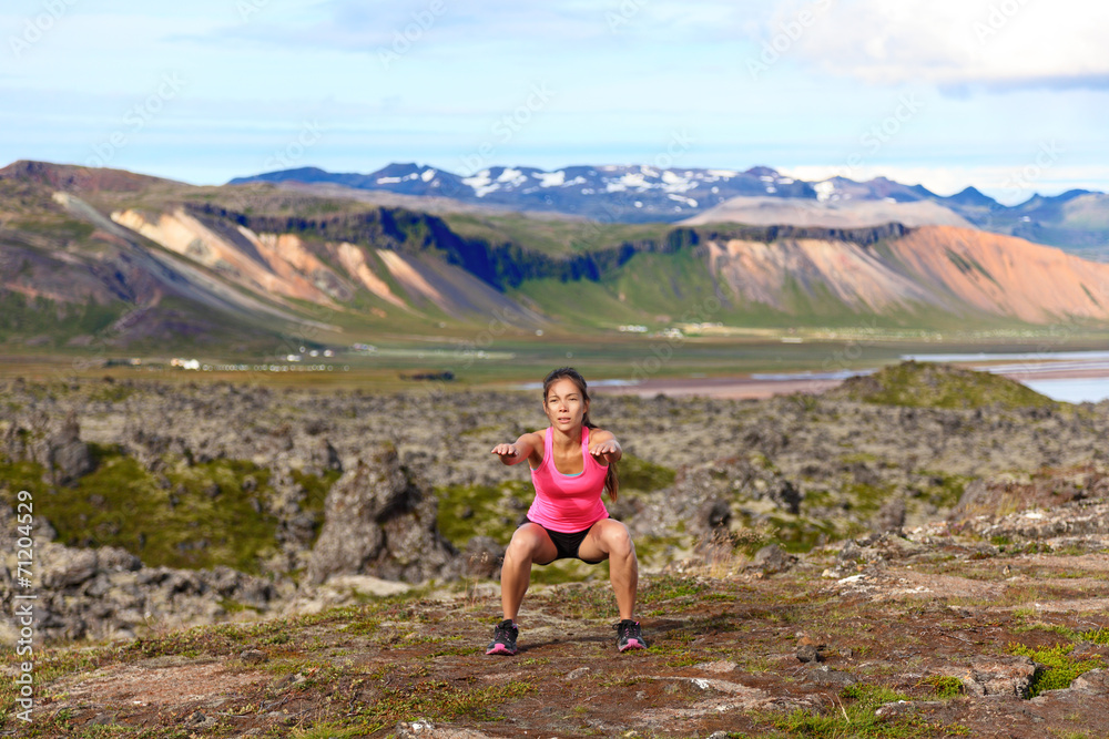Fitness girl exercising outdoors doing jump squat