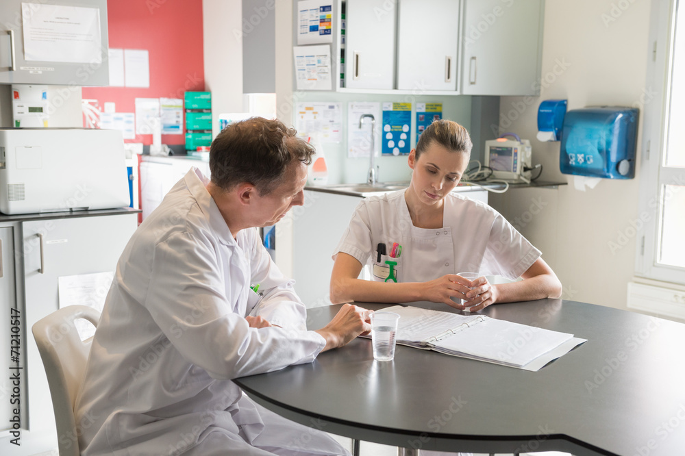 Doctor and nurse analyzing medical record in a hospital Doctor and nurse analyzing medical record in a hospital