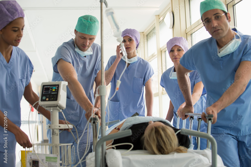 © onoky - Medical professionals pushing patient on gurney in a hospital © onoky - Medical professionals pushing patient on gurney in a hospital
