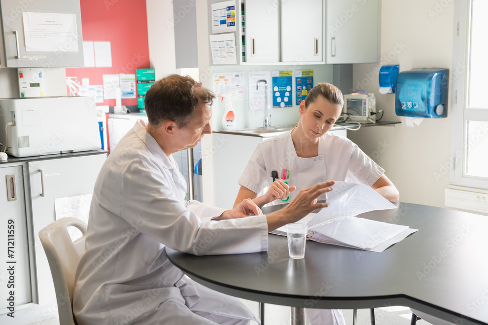 Doctor and nurse analyzing medical record in a hospital Doctor and nurse analyzing medical record in a hospital