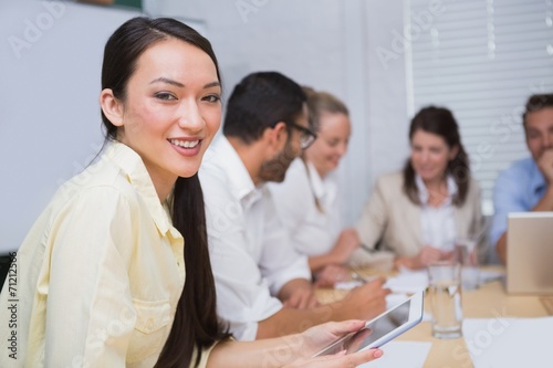 Businesswoman smiling at camera with team behind her