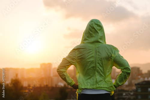 Athlete looking sunset over city skyline after exercising
