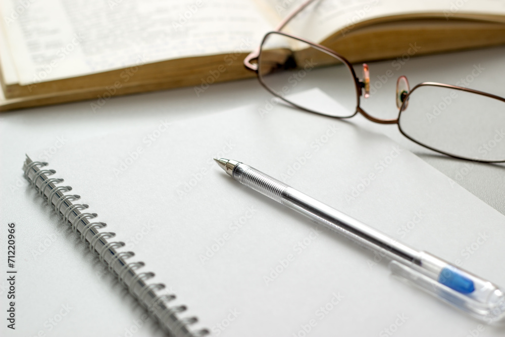 notebook with glasses and pen on table