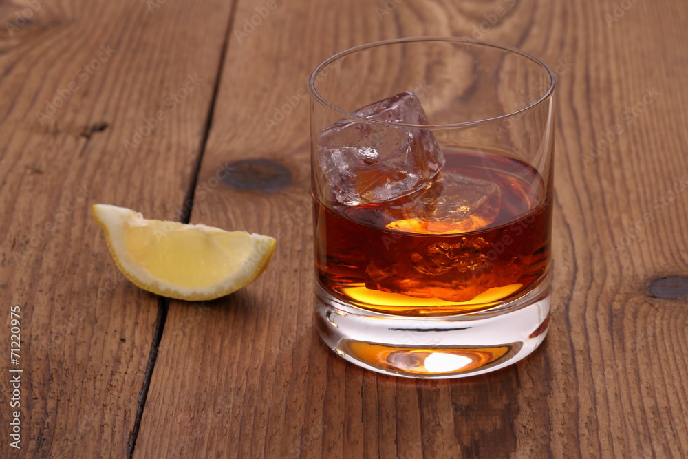Whiskey with ice cubes in glass on wood Whiskey with ice cubes in glass on wood