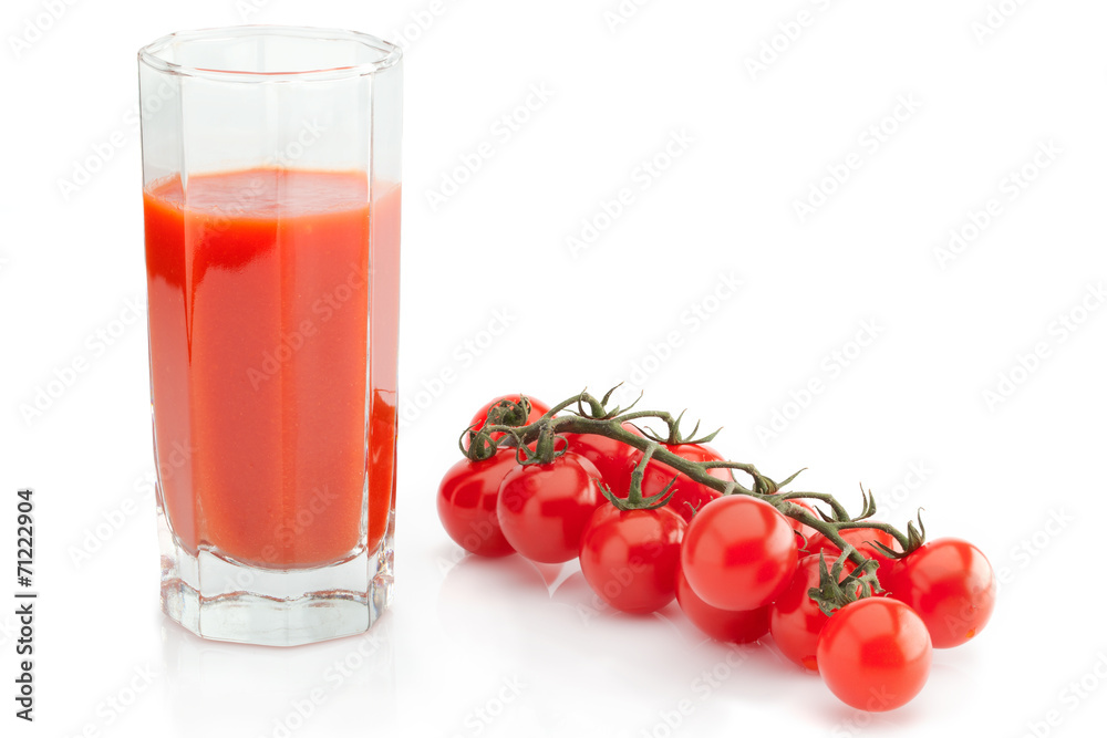 Faceted glass of tomato juice and branch of cherry tomatoes Faceted glass of tomato juice and branch of cherry tomatoes
