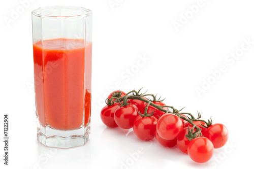 Faceted glass of tomato juice and branch of cherry tomatoes