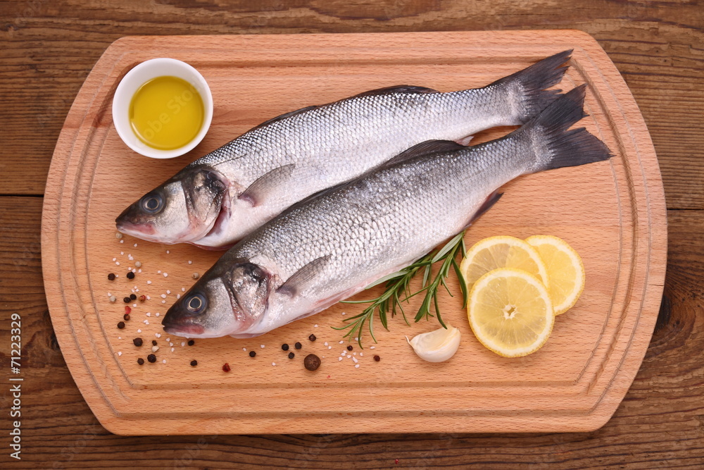 Two fresh moronidae fish on cutting board with ingredients Two fresh moronidae fish on cutting board with ingredients