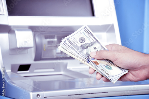 Hand holding money in front of ATM -retro style lighting effect 