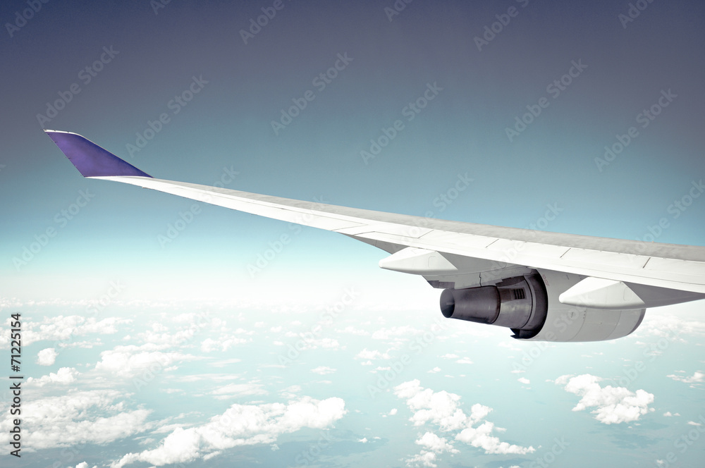 Fototapeta premium Airplane wing on blue sky background - retro lighting effect