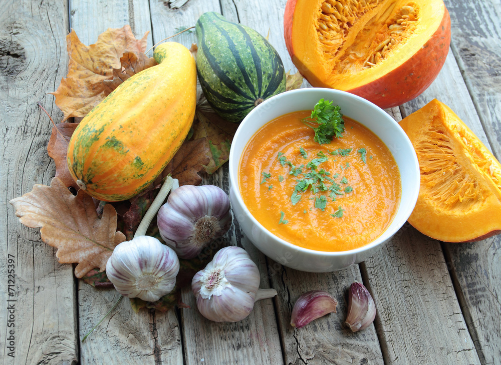 Bowl with pumpkin cream soup with parsley and whole pumpkin Bowl with pumpkin cream soup with parsley and whole pumpkin
