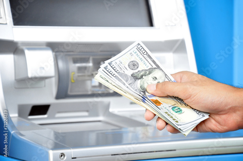 фотографія Hand holding money U.S. dollar (USD) bills in front of ATM
