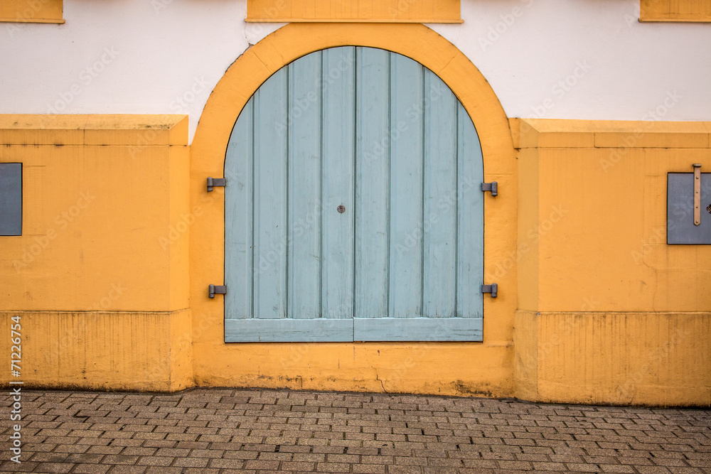 Hintergrund – gelbe verputzte Wand mit hellblauer Tür