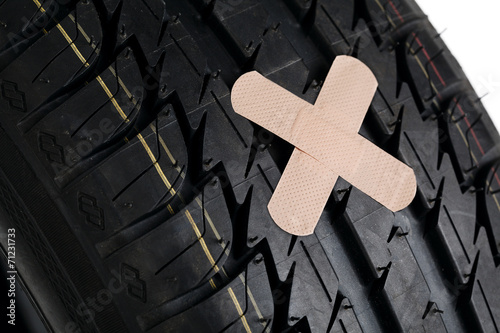 Canvas Print black new tire with patch on white