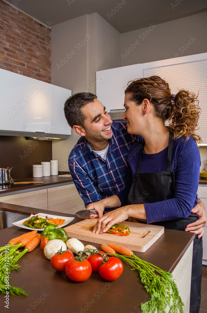 Couple hugging and preparing vegetables in the kitchen Couple hugging and preparing vegetables in the kitchen