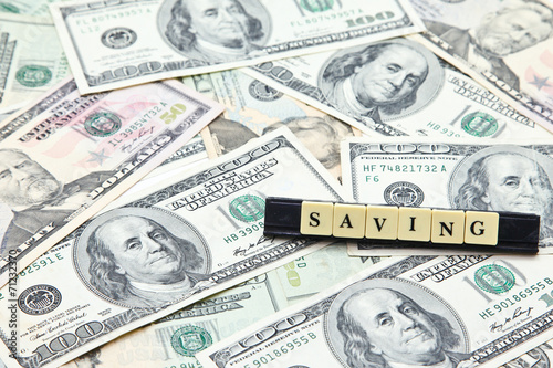 Word saving on pile of US dollar banknotes