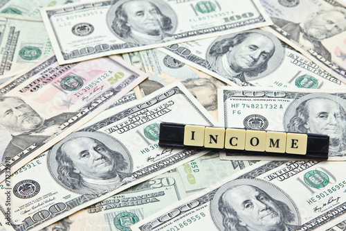 Word income on pile of US dollar banknotes