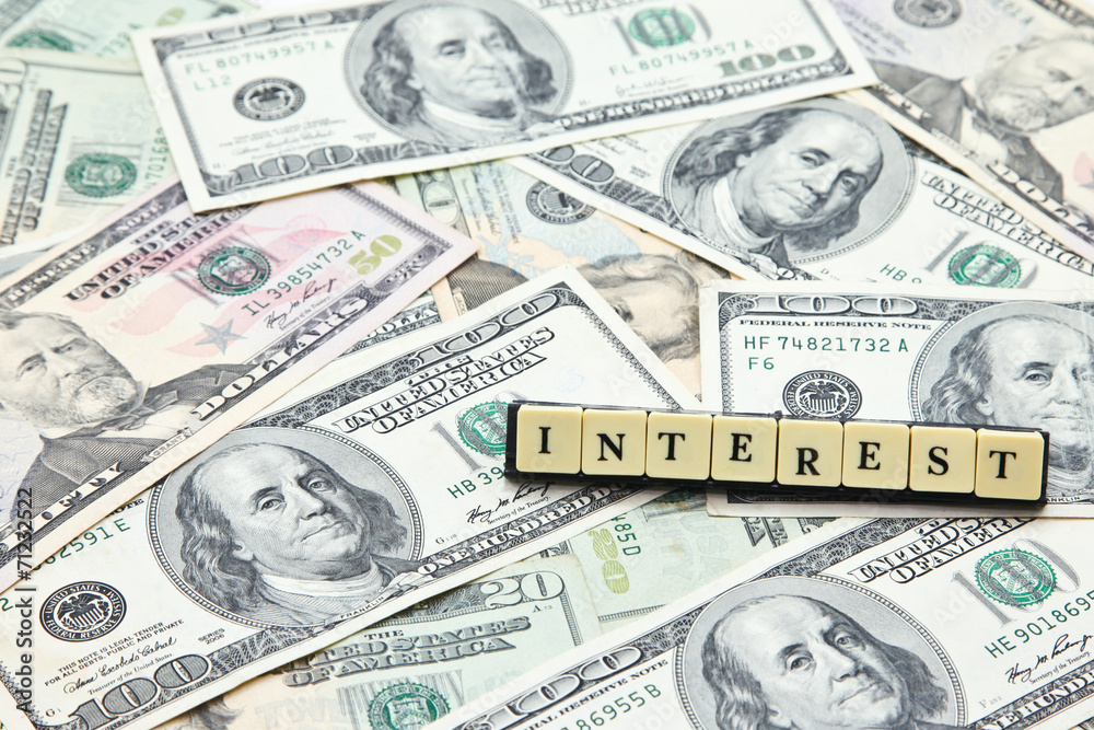 Word interest on pile of US dollar banknotes Word interest on pile of US dollar banknotes