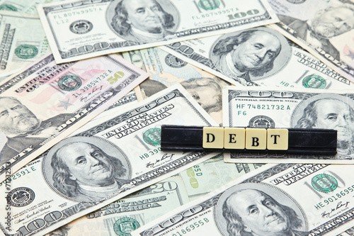 Word debt on pile of US dollar banknotes