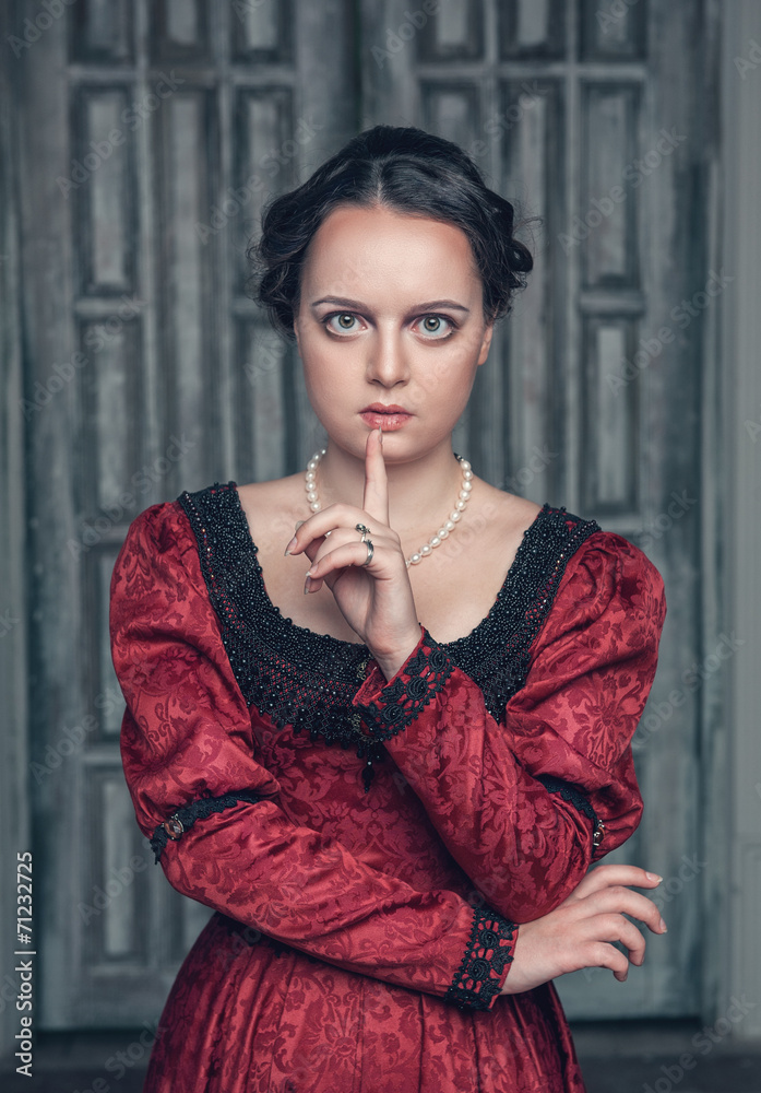 Fototapeta premium Beautiful medieval woman in red dress making silence gesture