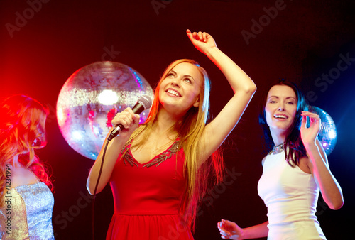 three smiling women dancing and singing karaoke © Syda Productions