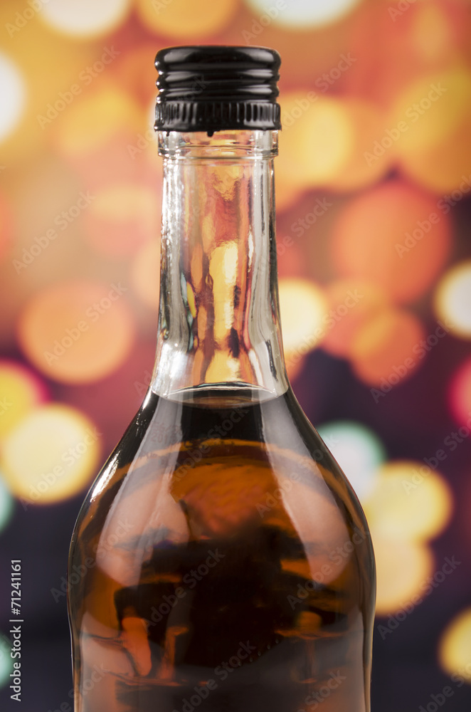 bottle of rum whiskey over defocused lights background