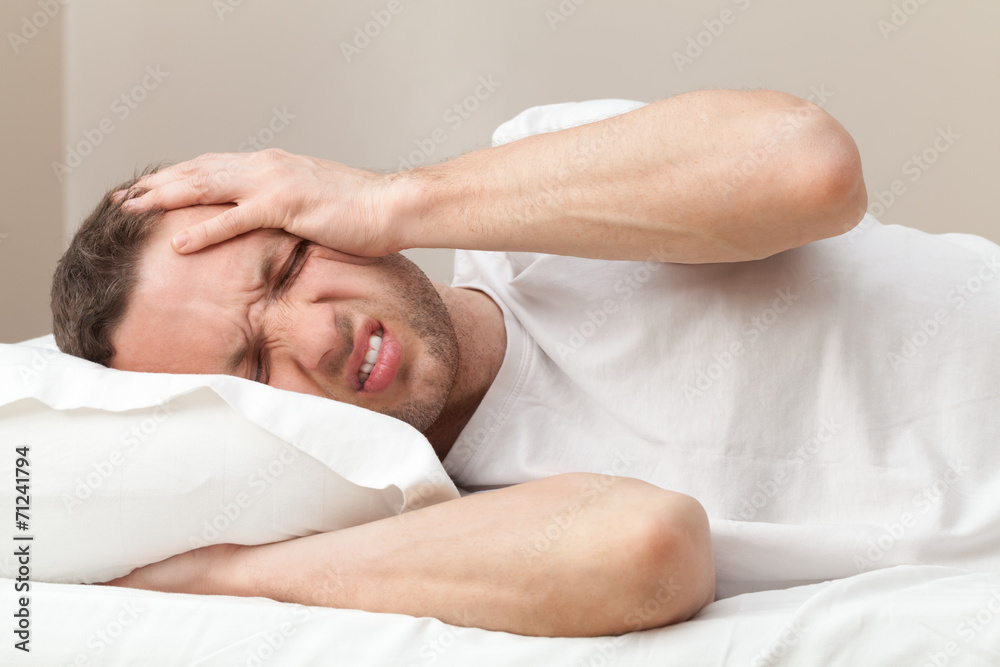 Portrait of Young Caucasian man in bed with headache Portrait of Young Caucasian man in bed with headache