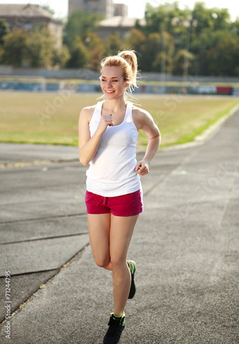 Smiling young woman jogging, training run outdoors