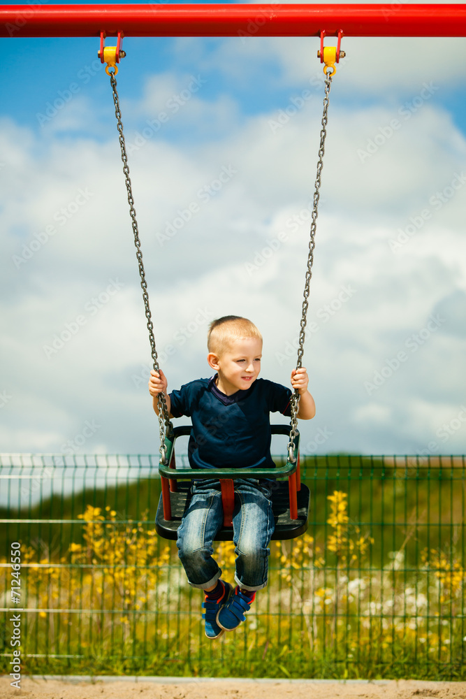 Little blonde boy child having fun on a swing outdoor Little blonde boy child having fun on a swing outdoor