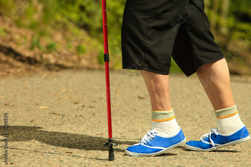 active senior legs in sneakers nordic walking in a park. © Voyagerix