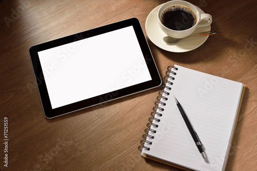Tablet computer with notepad and coffee cup on wooden background
