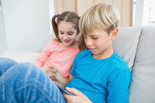 Happy siblings using tablet pc on sofa