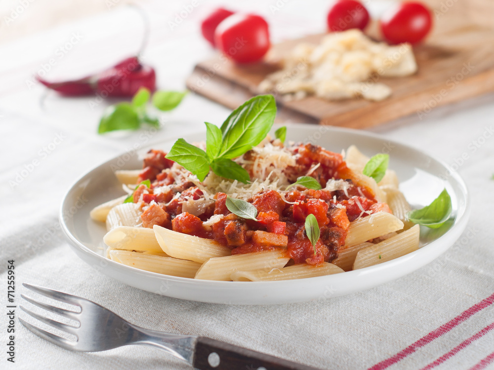 Penne pasta with sauce, cheese and basil, selective focus