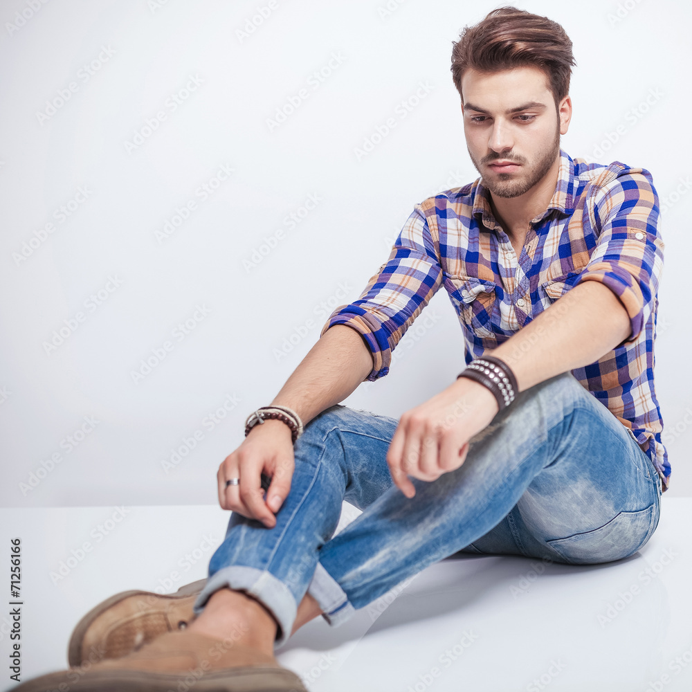 young man looking down while sitting on the floor