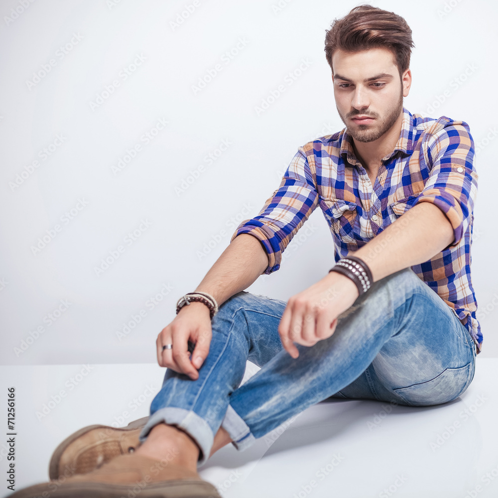 young man looking down while sitting on the floor young man looking down while sitting on the floor