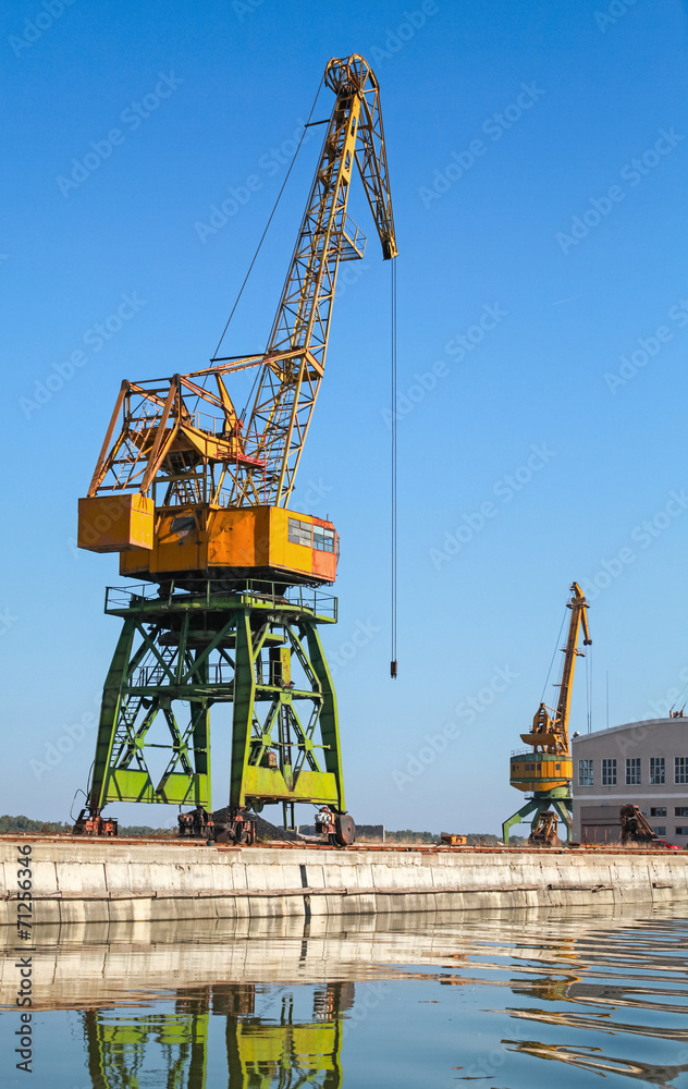 Big industrial harbor cranes works on the river coast Big industrial harbor cranes works on the river coast