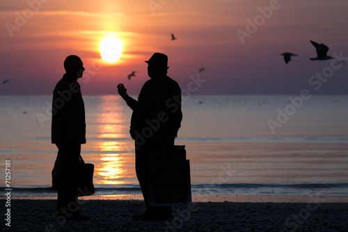 Silhouette of people talking on the beach at sunrise