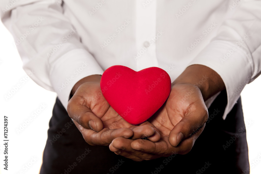 young dark-skinned man holding a heart shape object young dark-skinned man holding a heart shape object