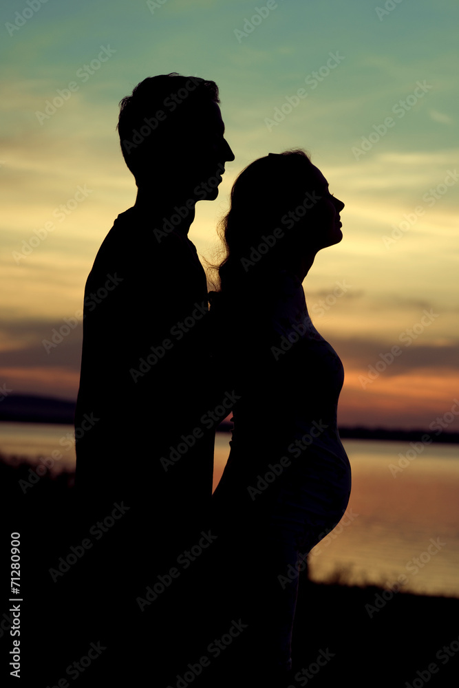 Silhouette of the man hugging his pregnant wife