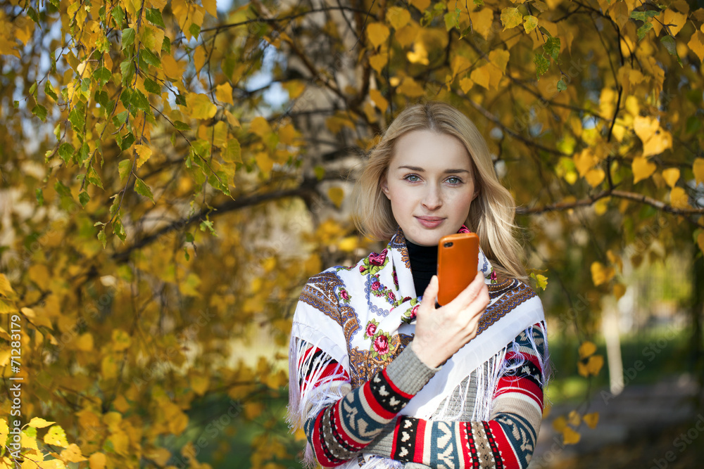 Happy beautiful girl photographed on a cell phone in autumn park Happy beautiful girl photographed on a cell phone in autumn park