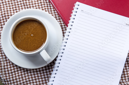 Cup of coffee and notepad on wooden table