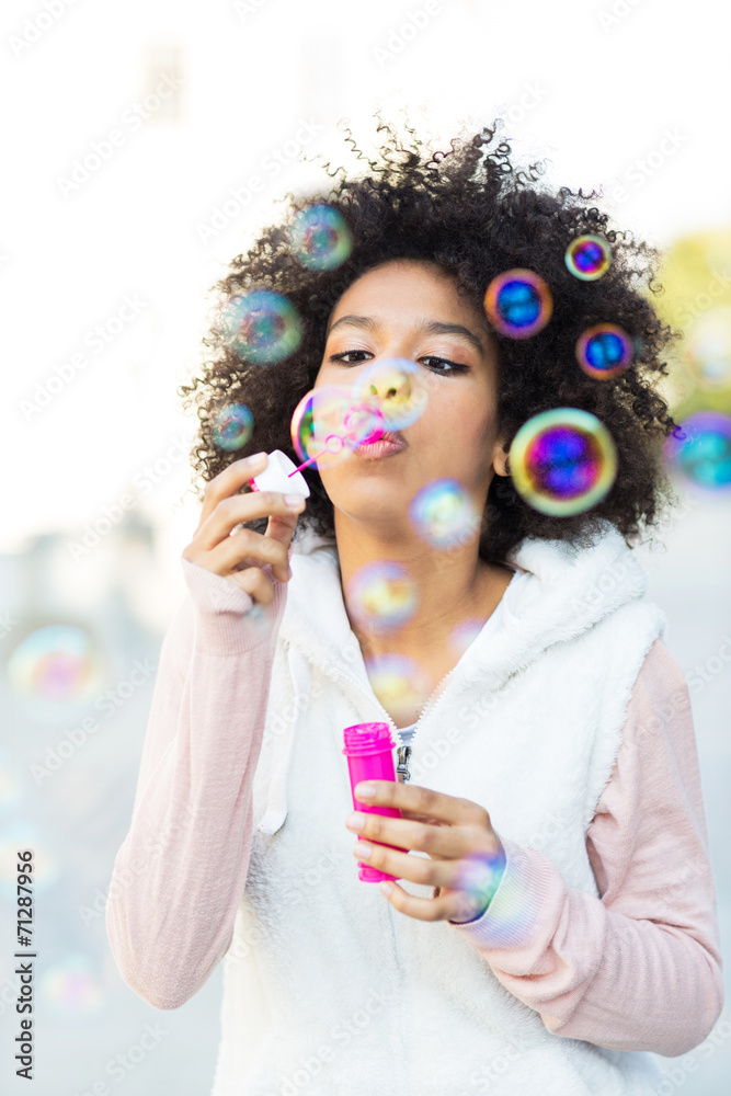 Afro woman blowing soap bubbles outdoors