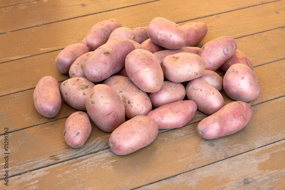 Ripe red potatoes on brown wooden floor close up Ripe red potatoes on brown wooden floor close up
