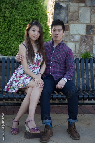 Asian couple sitting together on an iron bench © Allen Penton