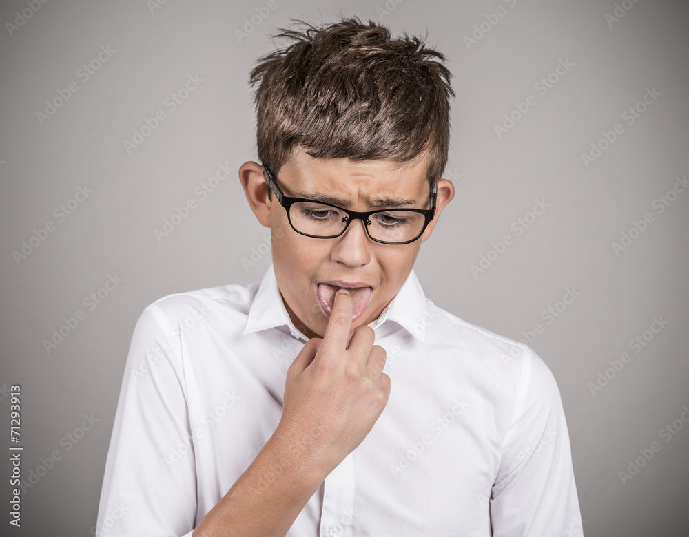 annoyed boy with finger in mouth, disgusted on grey background annoyed boy with finger in mouth, disgusted on grey background